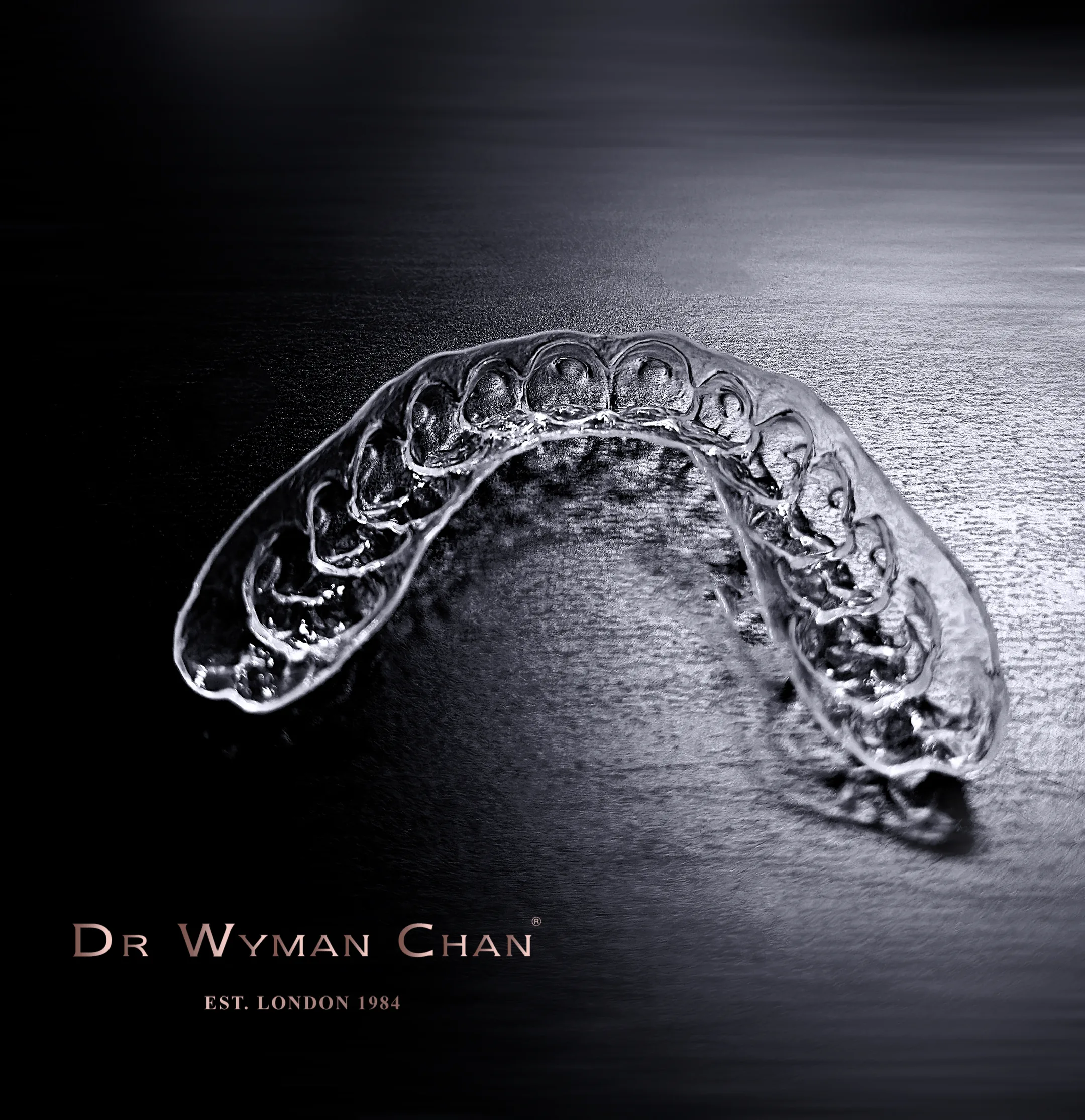 A single clear Perfect Tray photographed on a dramatic black surface, with the Dr Wyman Chan EST. London 1984 mark beneath.